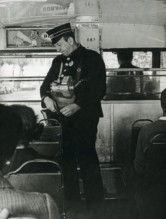 1967. Con rígida uniformidad, gorra incluida, un cobrador desempeña su trabajo a bordo de un autobús (con el volante a la derecha)