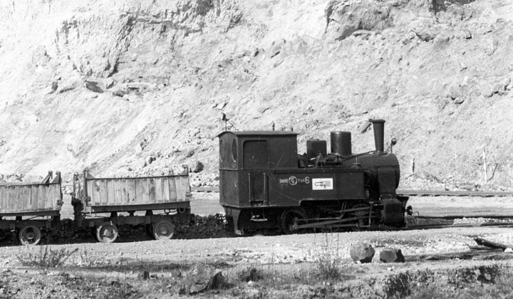 Locomotora de vapor tipo 030 de la empresa Constructora Internacional S.A. y dos vagones abiertos junto a un peñasco, detenidos en la estación de El Musel de la Junta de Obras del Puerto de Gijón. Archivo Histórico Ferroviario, FN-27046